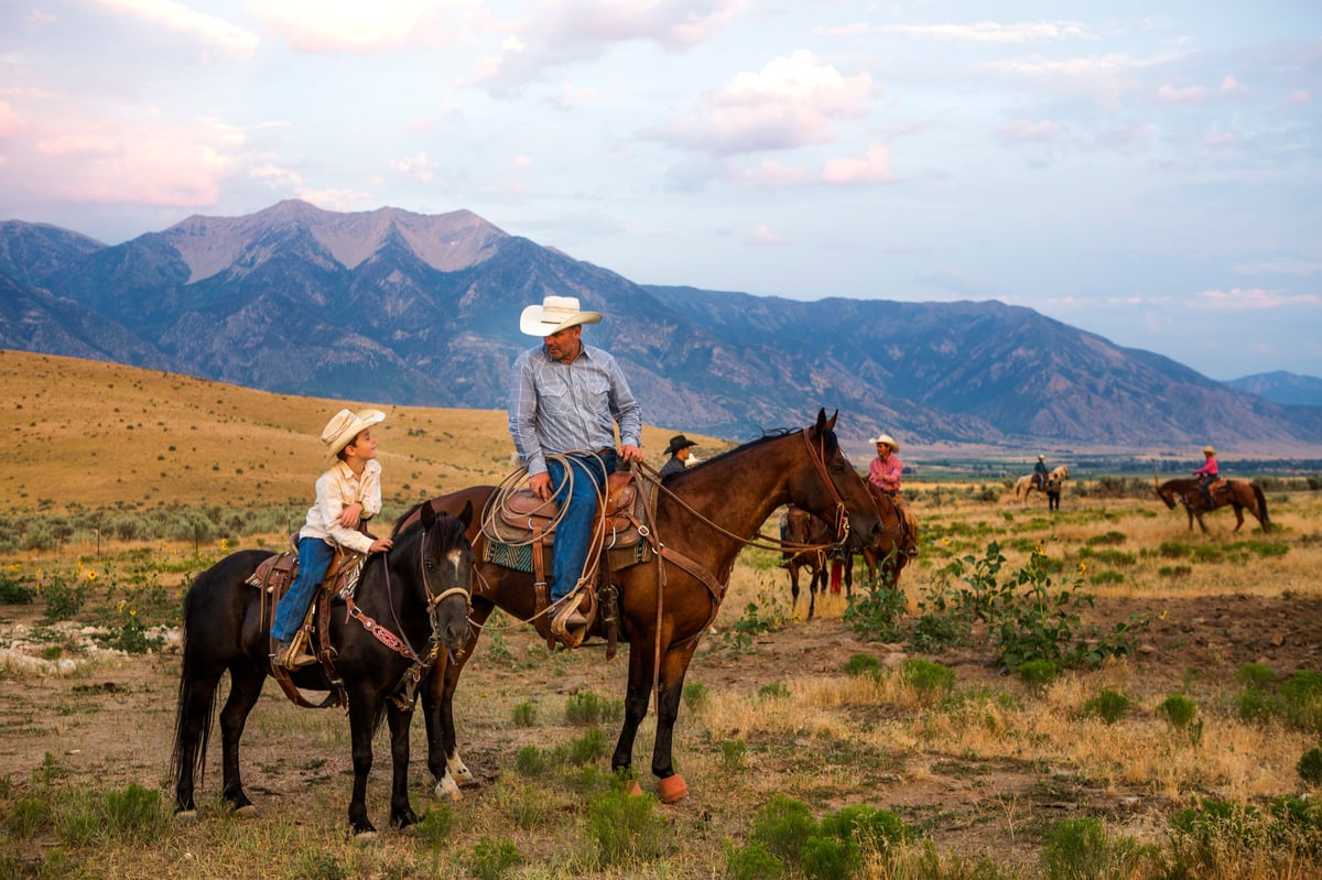 A father and son on horseback looking out over their ranch